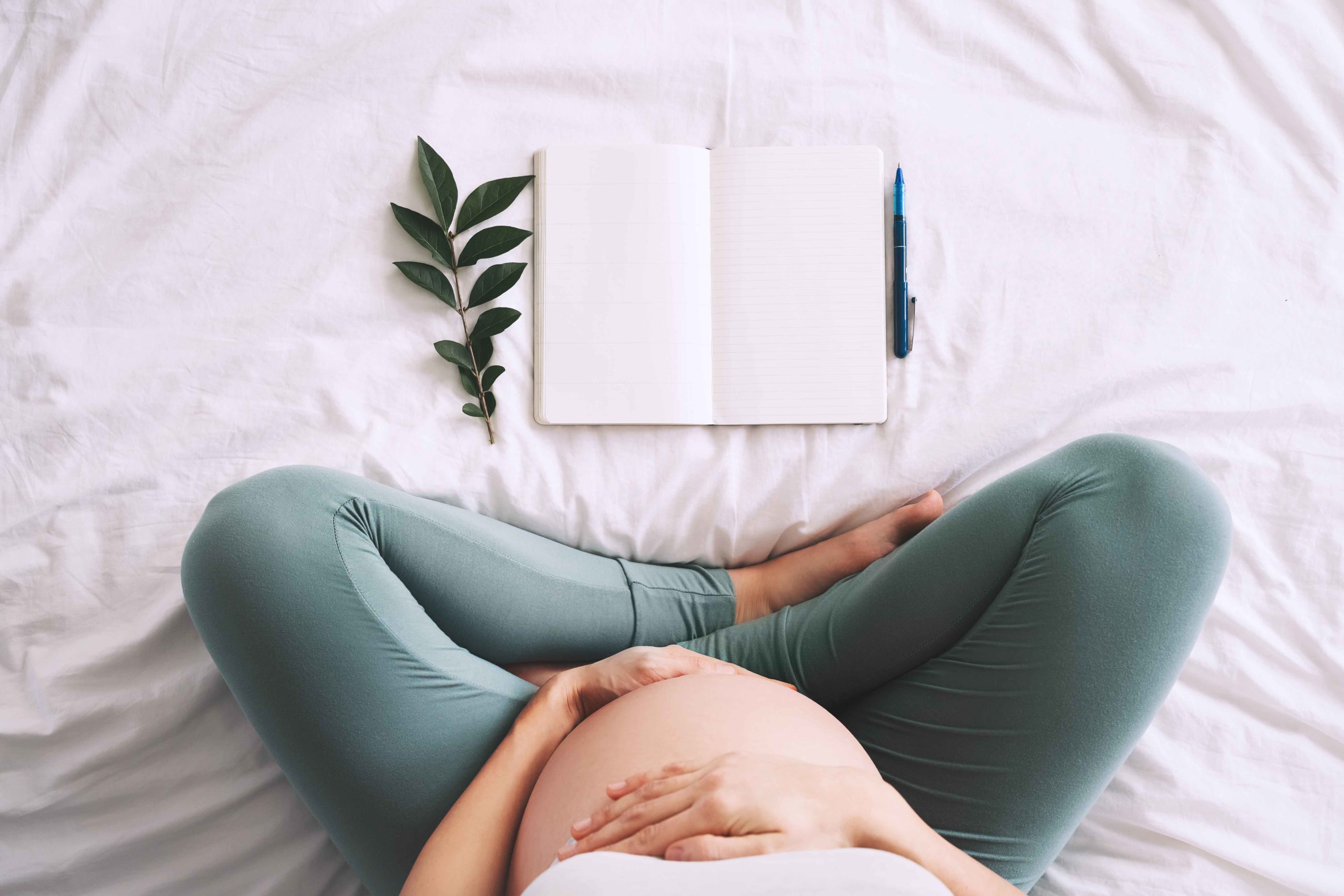 Pregnant woman sitting cross-legged on a bed