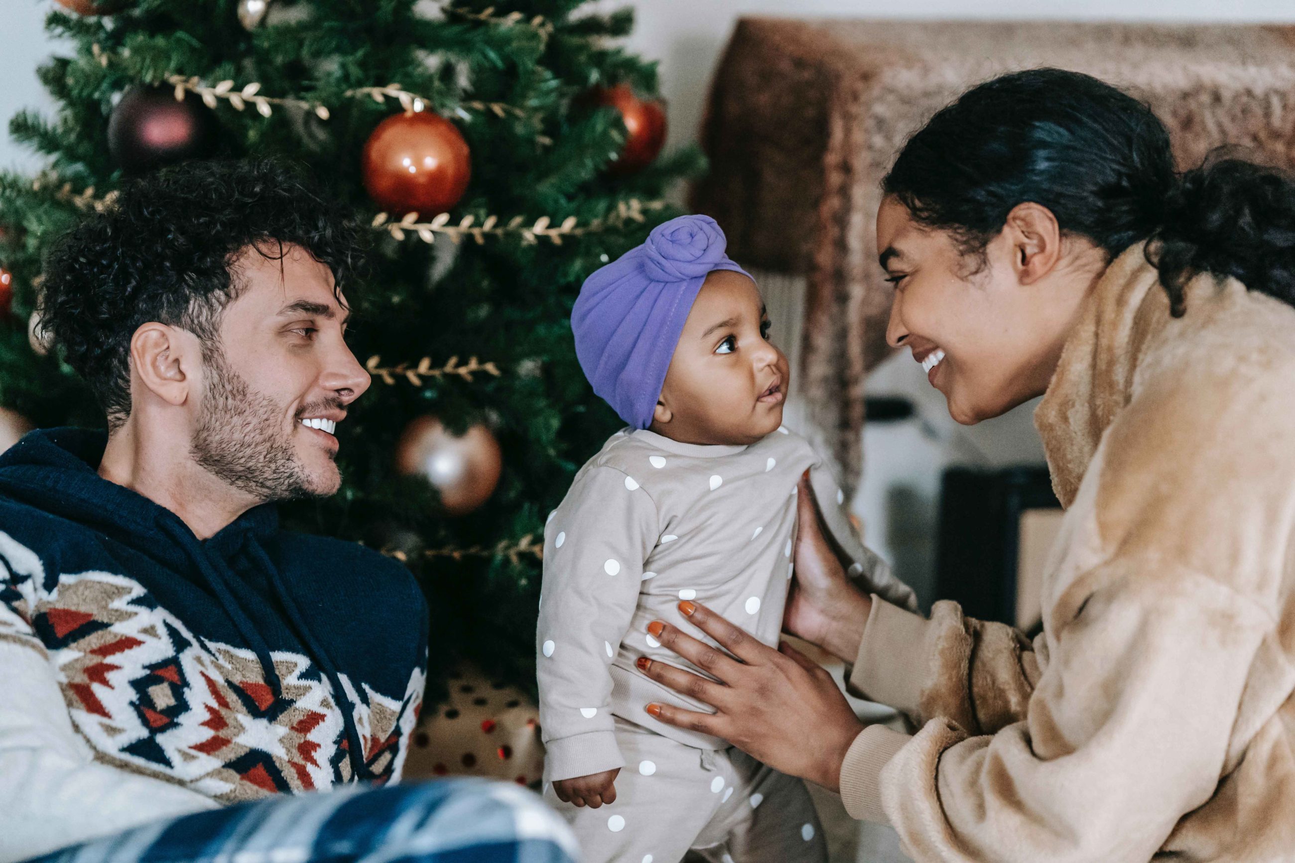 Papa, maman et bébé à la maison sous le sapin de Noël