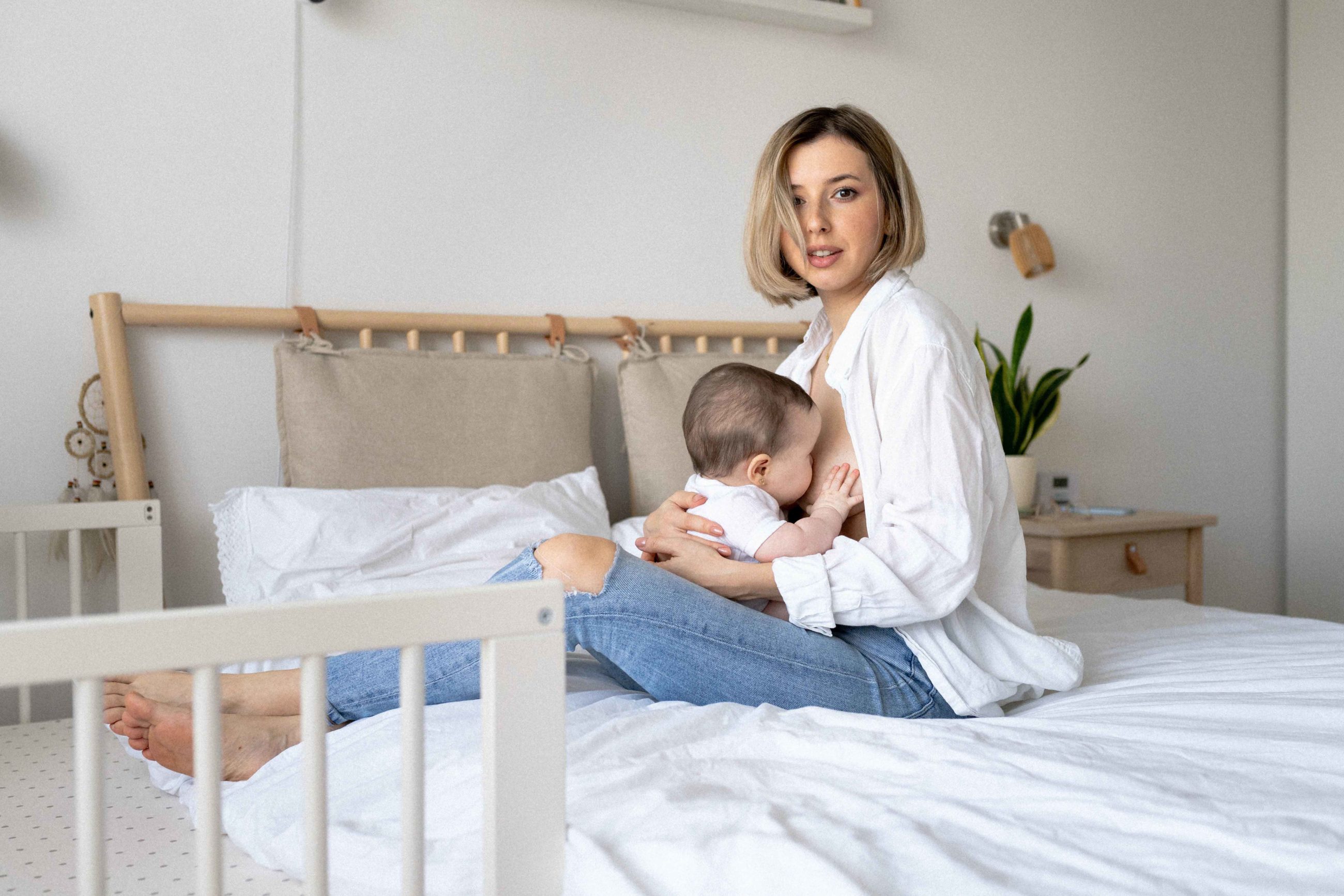 Mère assise sur un lit avec son enfant en train de téter 